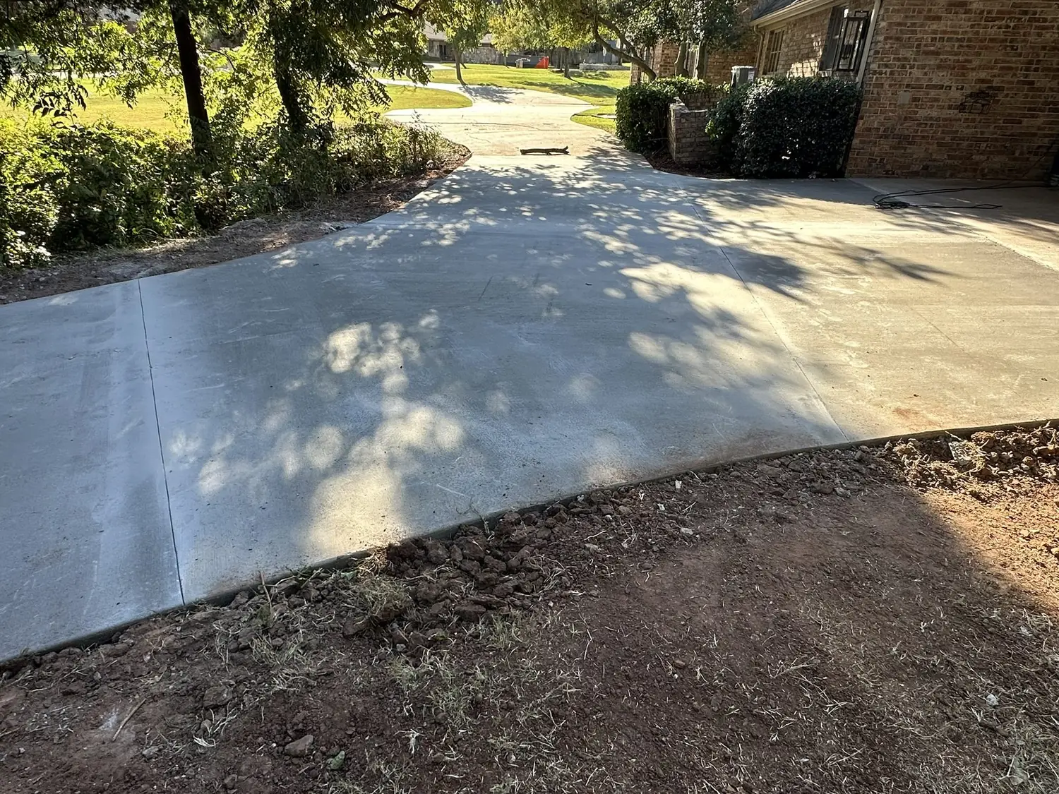 Curved residential concrete driveway with a smooth broom finish, by Lucky's Concrete