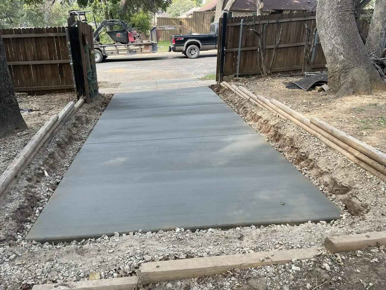 Freshly poured broom-finish concrete patio in a fenced backyard